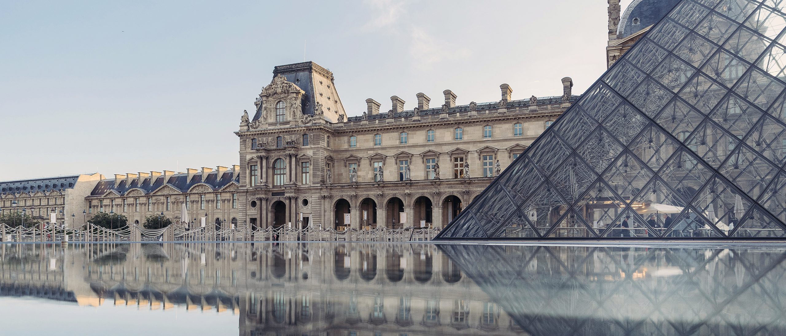 El Louvre y su pirámide de vidrio reflejados en el agua